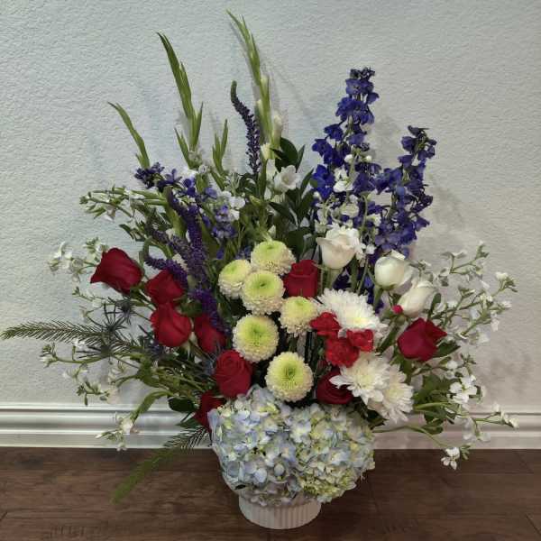 Mixed bouquet in a white vase with red, white, blue, and green flowers