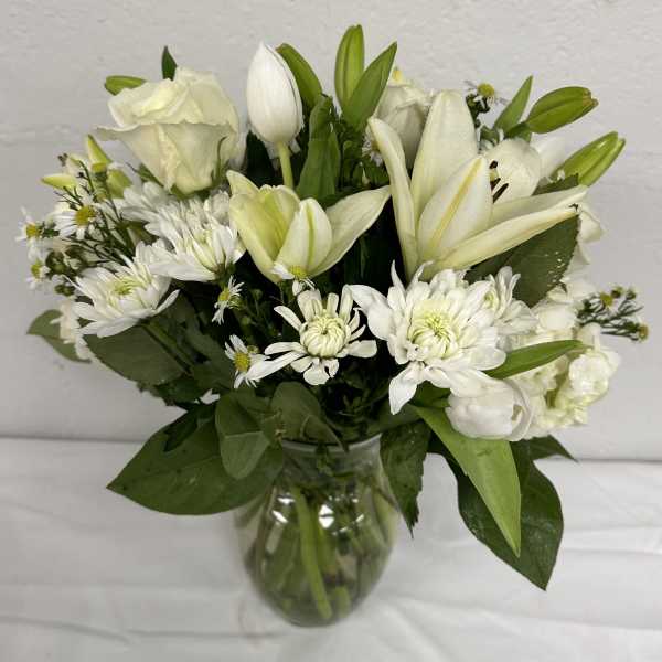 White lilies and daisies arranged in a clear glass vase