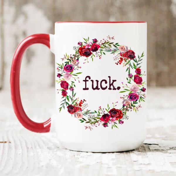 White mug with red handle and floral wreath around text