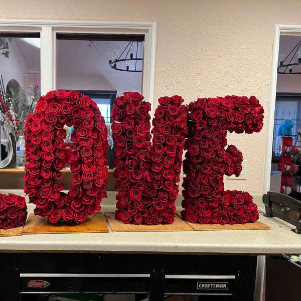 Large red rose letters spelling "LOVE" on wooden bases