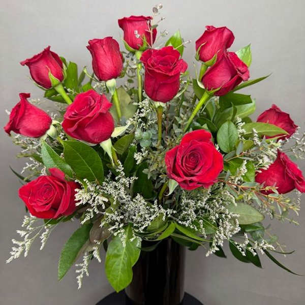 Bouquet of red roses with white filler in a black vase