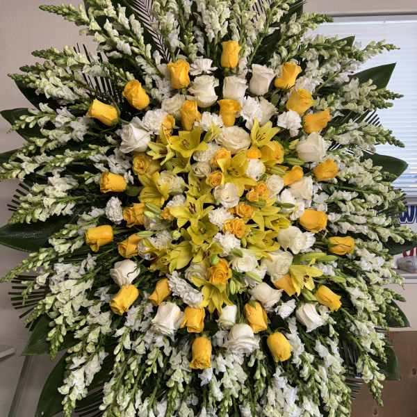 Large yellow and white floral standing spray with roses and lilies
