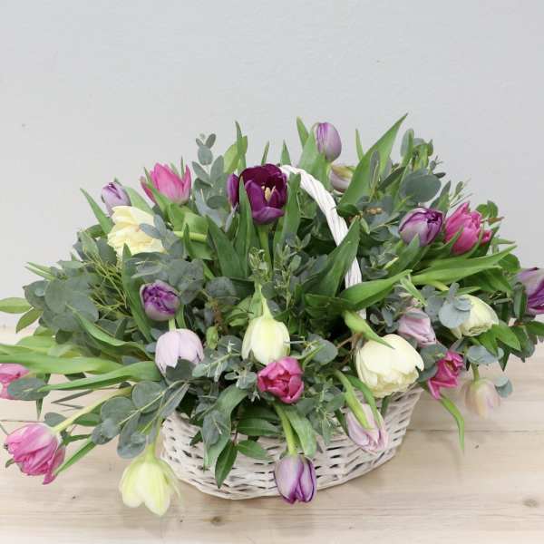 Basket of pink, purple, and white tulips with greenery