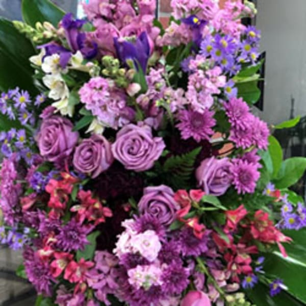 Large bouquet of purple and pink flowers with broad green leaves
