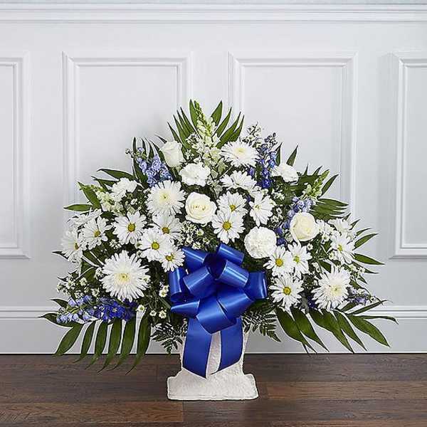 White and blue floral standing spray with a blue ribbon on a pedestal