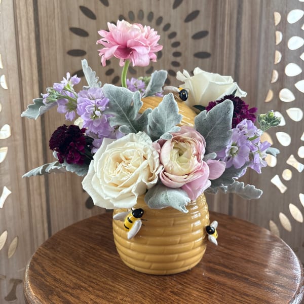 Pink and white flowers arranged in a yellow bee vase