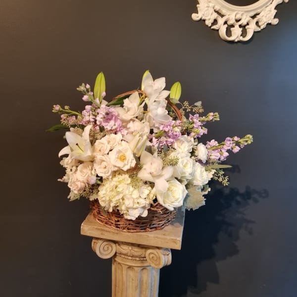 White and pale lavender floral arrangement in a wicker basket