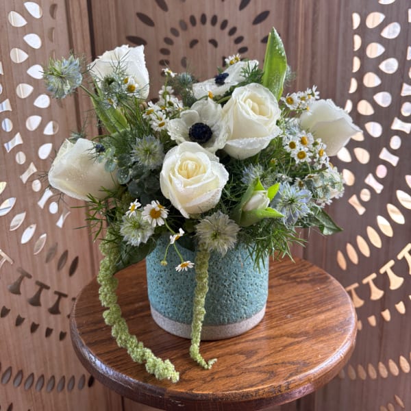 White roses and small daisies in a blue vase