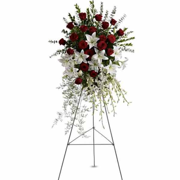 Standing floral spray with red roses and white lilies on a metal easel