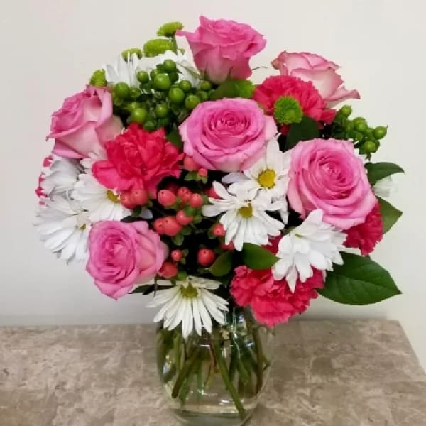 Pink roses and white daisies arranged in a glass vase