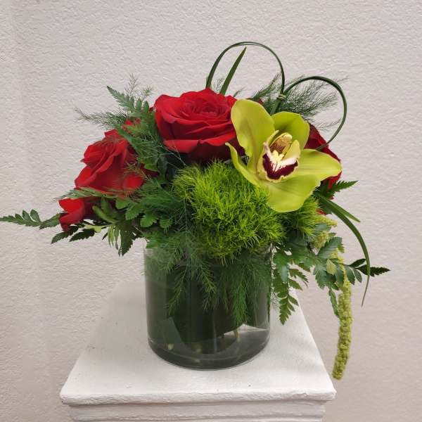 Red roses and a green orchid in a glass vase