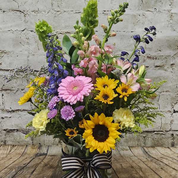 Mixed bouquet in a glass vase with sunflowers, gerberas, and snapdragons