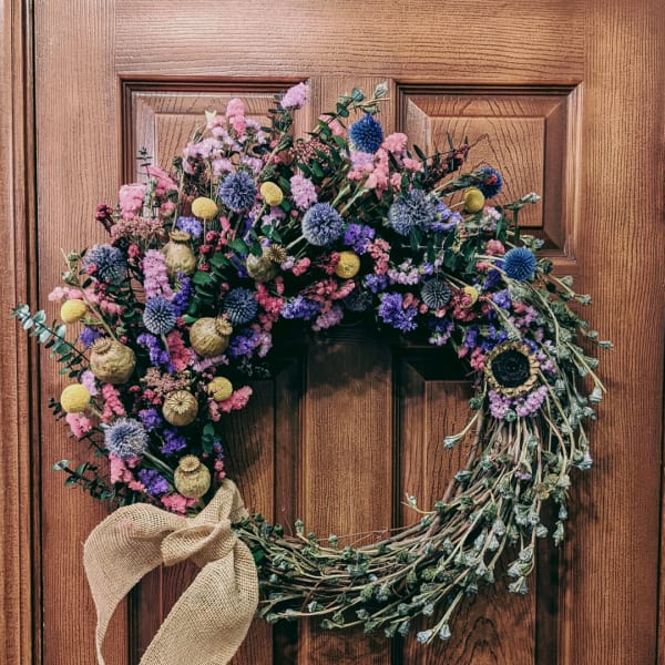 Heart-shaped floral wreath with a burlap bow on a wooden door
