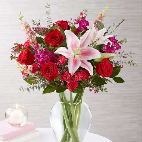 Bouquet of red roses and pink lilies in a clear glass vase