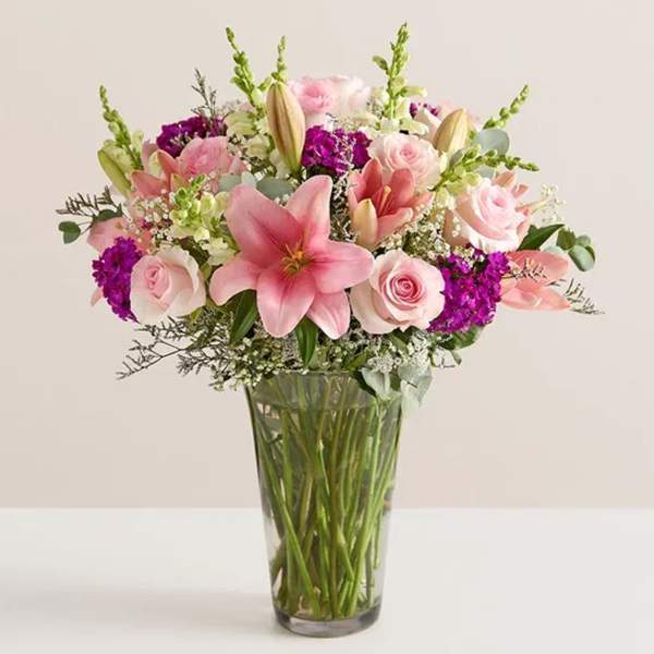 Pink lilies and roses arranged in a clear glass vase
