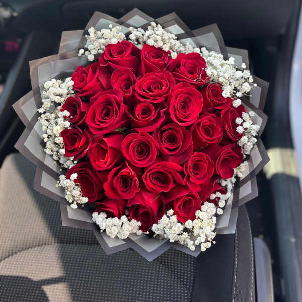Bouquet of red roses with white baby's breath in dark wrap
