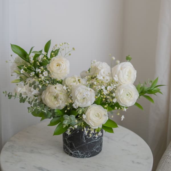 White ranunculus arrangement in a black marble vase