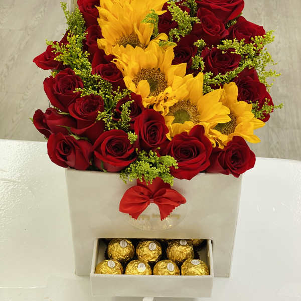 Red roses and yellow sunflowers in a gift box with chocolates