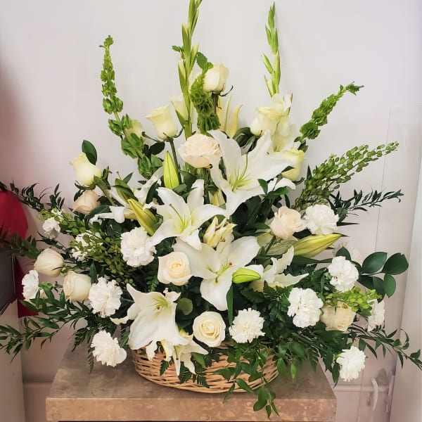 White lilies and roses arranged in a wicker basket