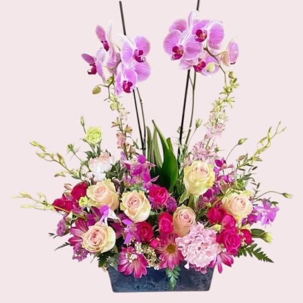 Pink and purple floral arrangement in a dark rectangular container