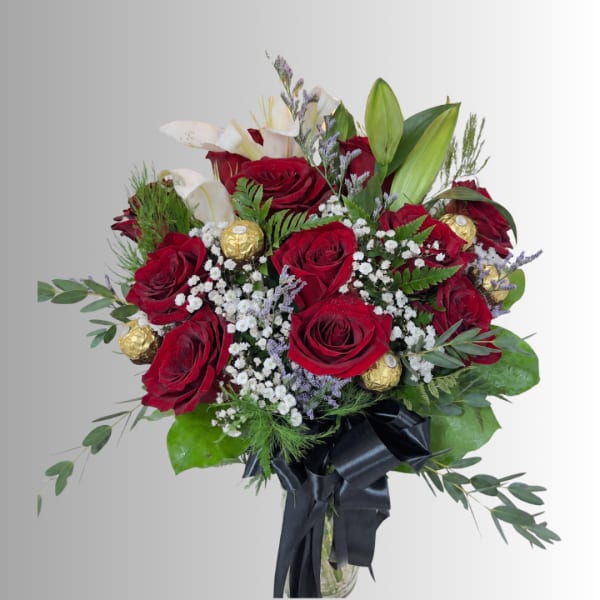 Bouquet of red roses, white lilies, and gold chocolates in a glass vase