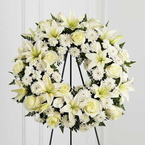 Standing wreath of white lilies, roses, and mums on a metal easel stand