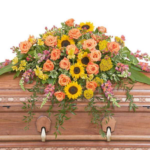 Casket spray with peach roses and yellow sunflowers