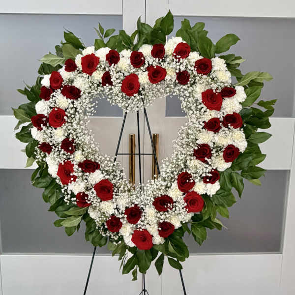 Heart-shaped wreath of red and white flowers on a stand