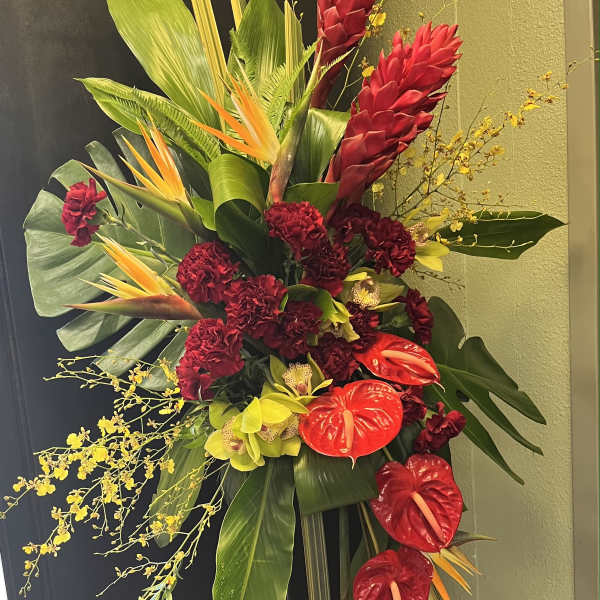 Tall tropical floral spray with red blooms and yellow orchids on a stand