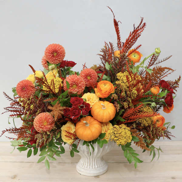 Autumn floral arrangement with pumpkins in a white vase