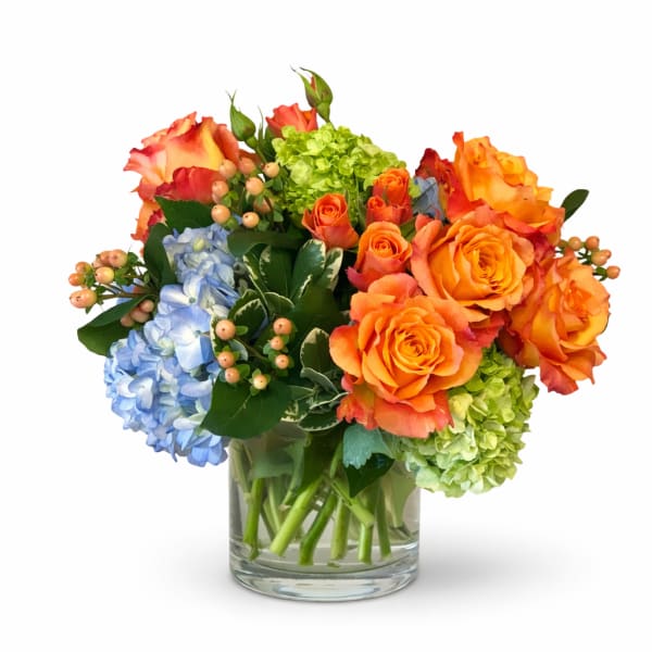 Bouquet of orange roses, blue hydrangeas, and green hydrangeas in a glass vase