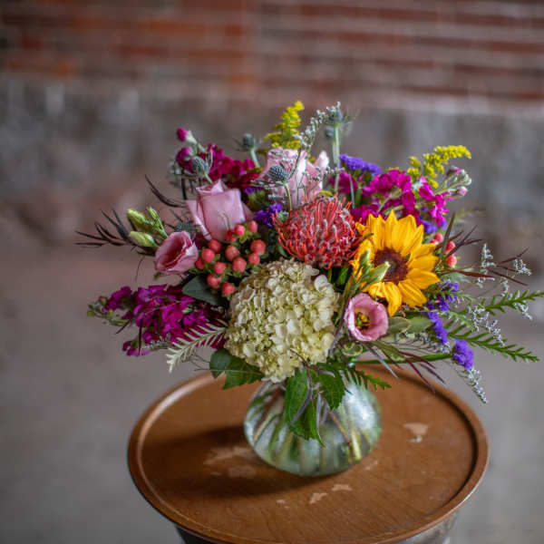 Mixed bouquet in a glass vase with a sunflower and pink blooms