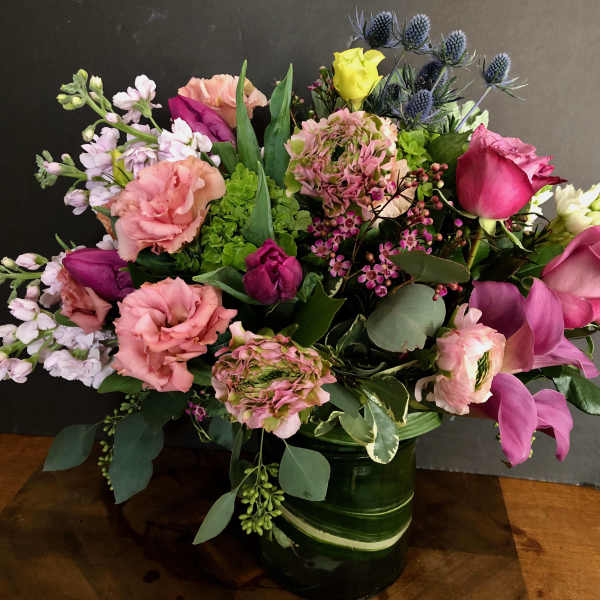 Mixed bouquet of pink, purple, and yellow flowers in a green vase