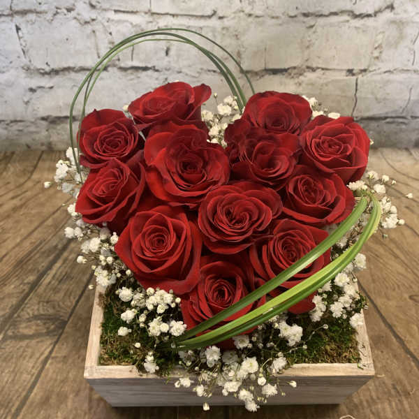 Red roses arranged in a square wooden box with white baby's breath