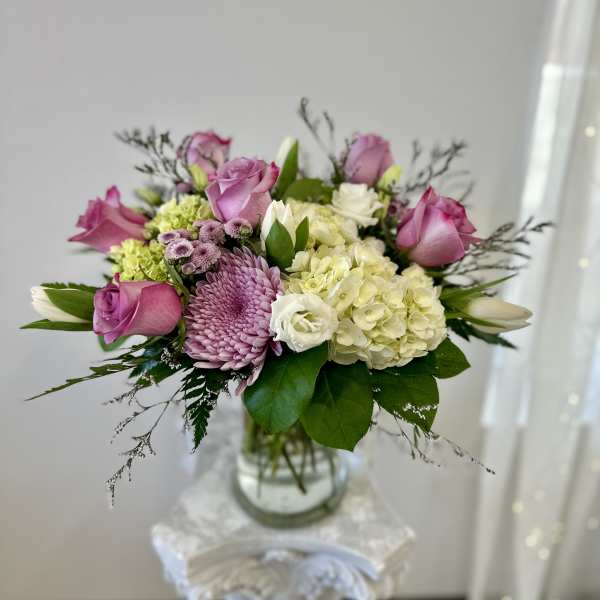 Pink roses and lavender blooms in a glass vase