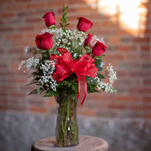Bouquet of red roses and baby's breath in a glass vase with a red bow