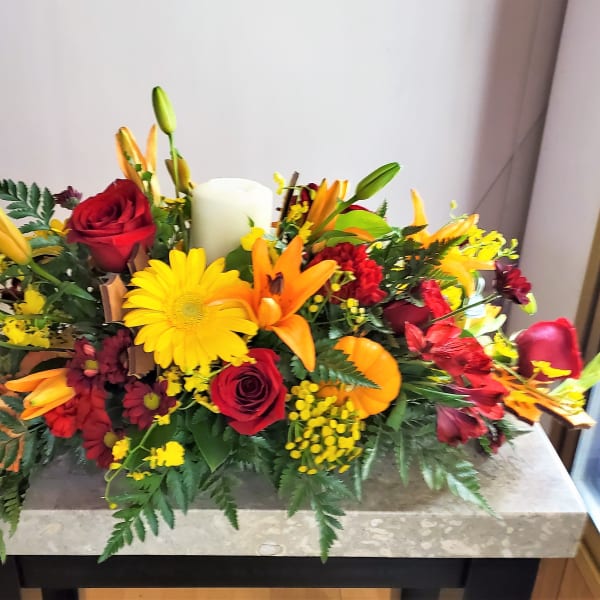 Mixed bouquet with red roses, yellow daisies, and orange lilies in a low arrangement