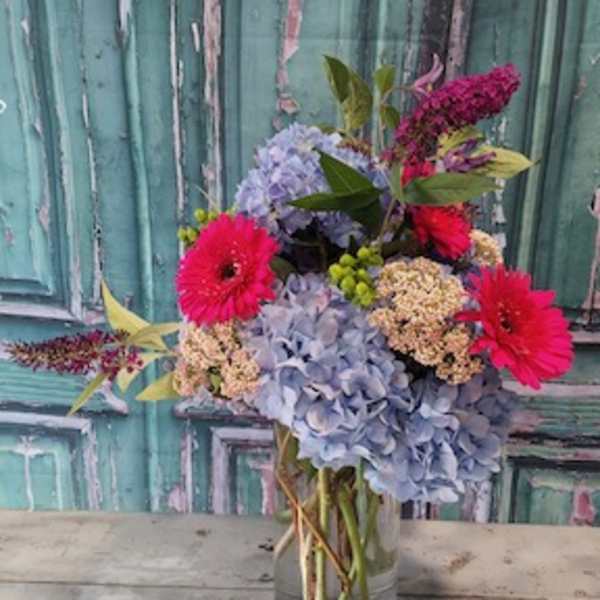 Bouquet of blue hydrangeas and bright pink gerbera daisies in a glass vase