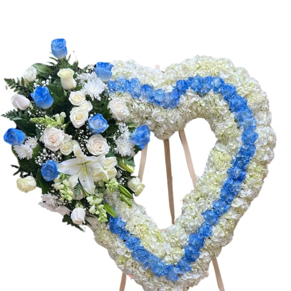 Heart-shaped floral wreath on an easel with blue and white flowers