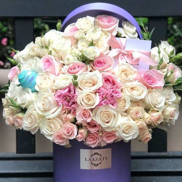 Bouquet of pink and white roses in a purple hatbox with a ribbon