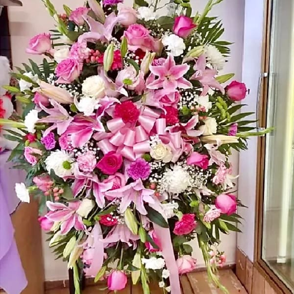 Large pink and white floral standing arrangement with a ribbon bow