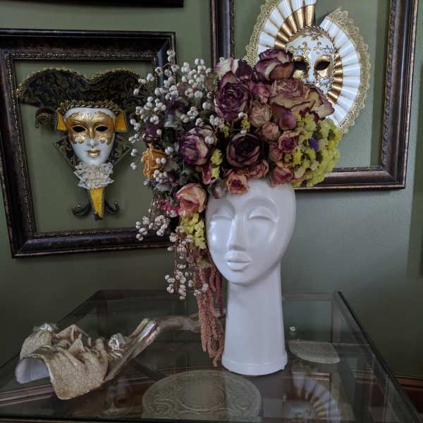 Floral headpiece on a white mannequin bust with purple and cream roses