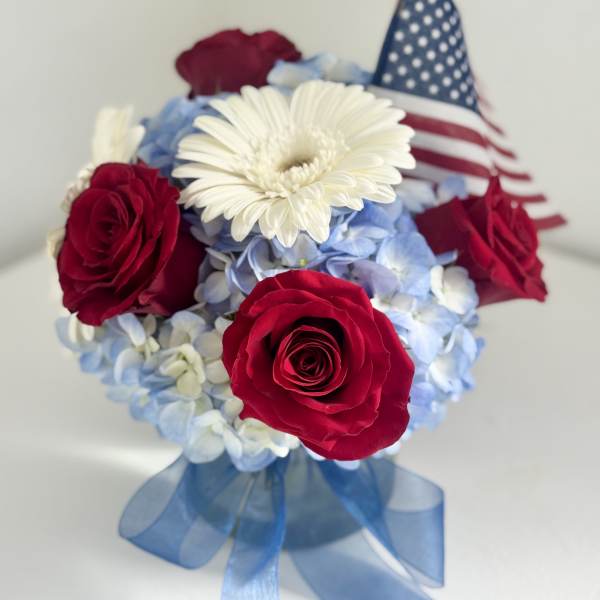 Red roses and white daisy bouquet with a small American flag