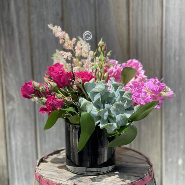 Pink roses and carnations arranged with a succulent in a black vase