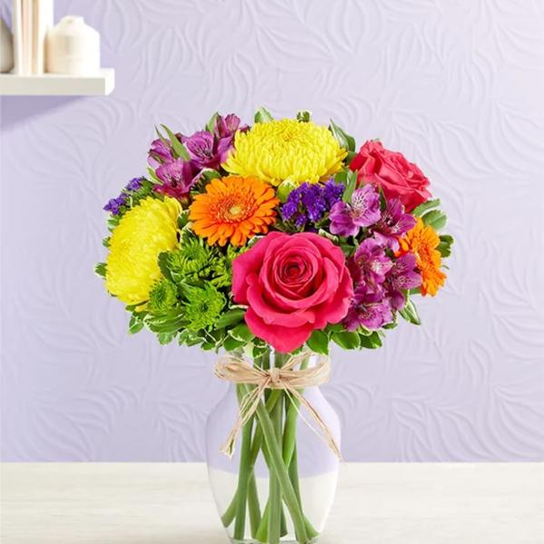 Colorful bouquet of roses, gerbera daisies, and chrysanthemums in a glass vase