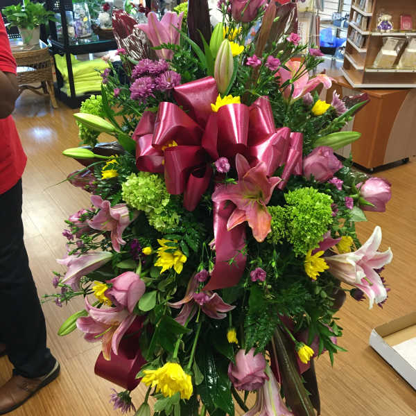 Large mixed bouquet with pink lilies, yellow daisies, and a magenta ribbon