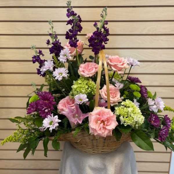 Basket arrangement of pink roses and purple flowers