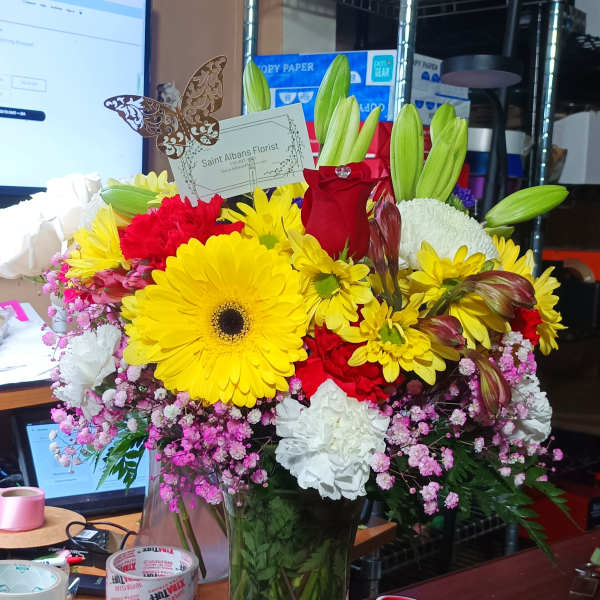Mixed bouquet in a clear glass vase with yellow, red, and white flowers