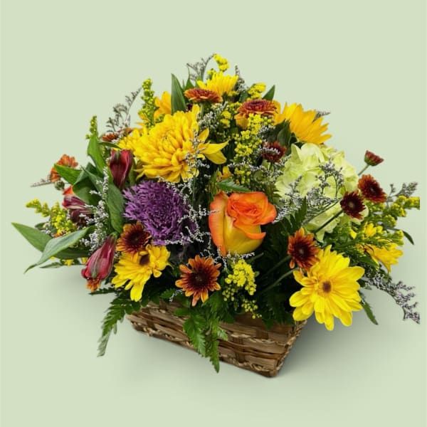 Mixed flower arrangement in a wicker basket with yellow and orange blooms