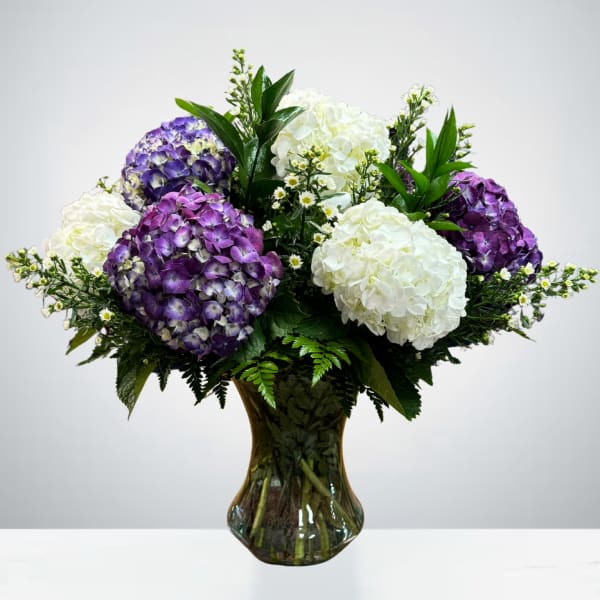 Purple and white hydrangea arrangement in a glass vase
